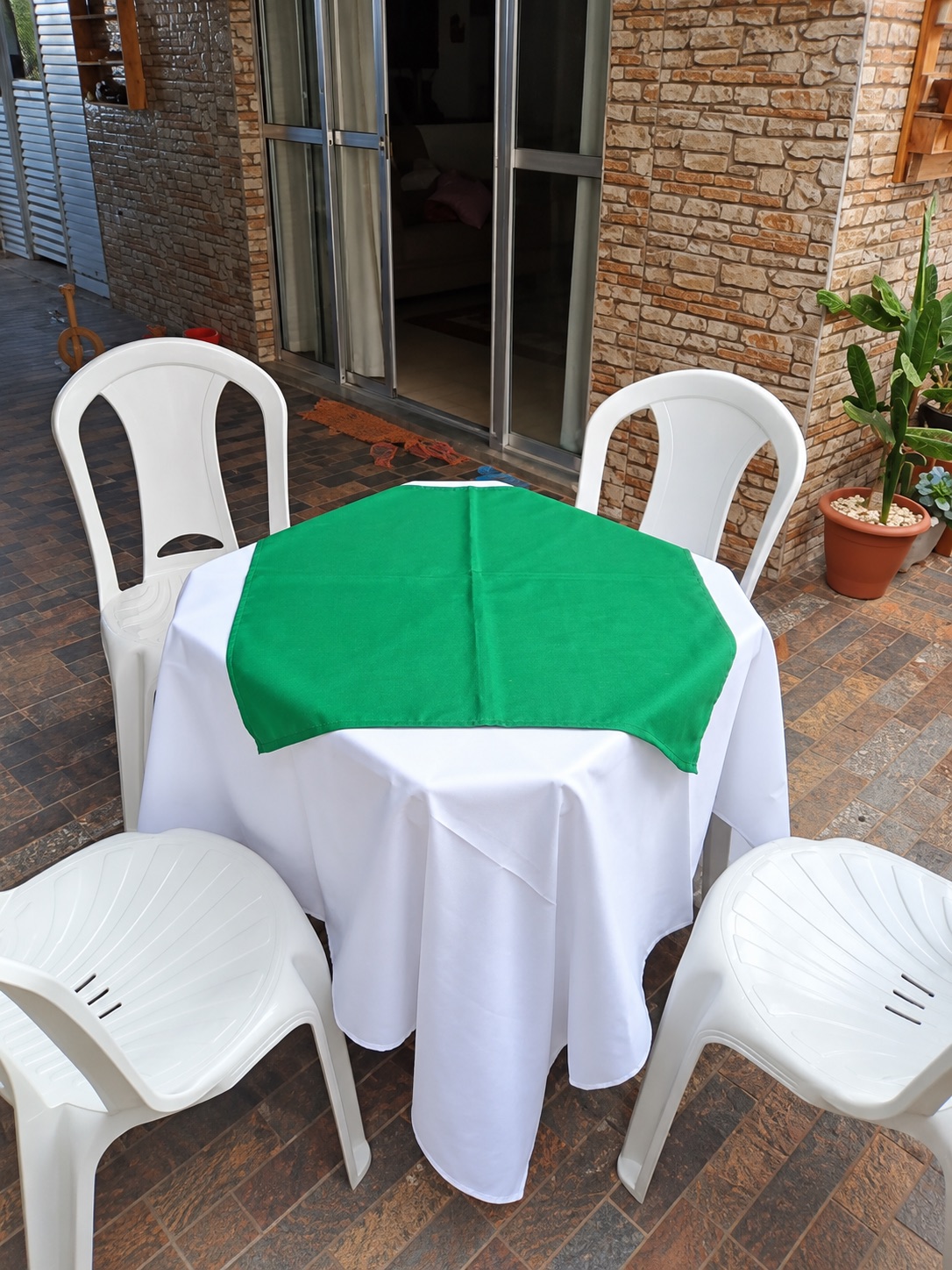 Conjunto de cadeiras brancas ao redor de mesa com toalha verde da Labrego Locações
