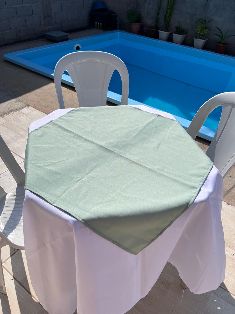 Toalha verde-clara com toalha branca em mesa da Labrego Locações